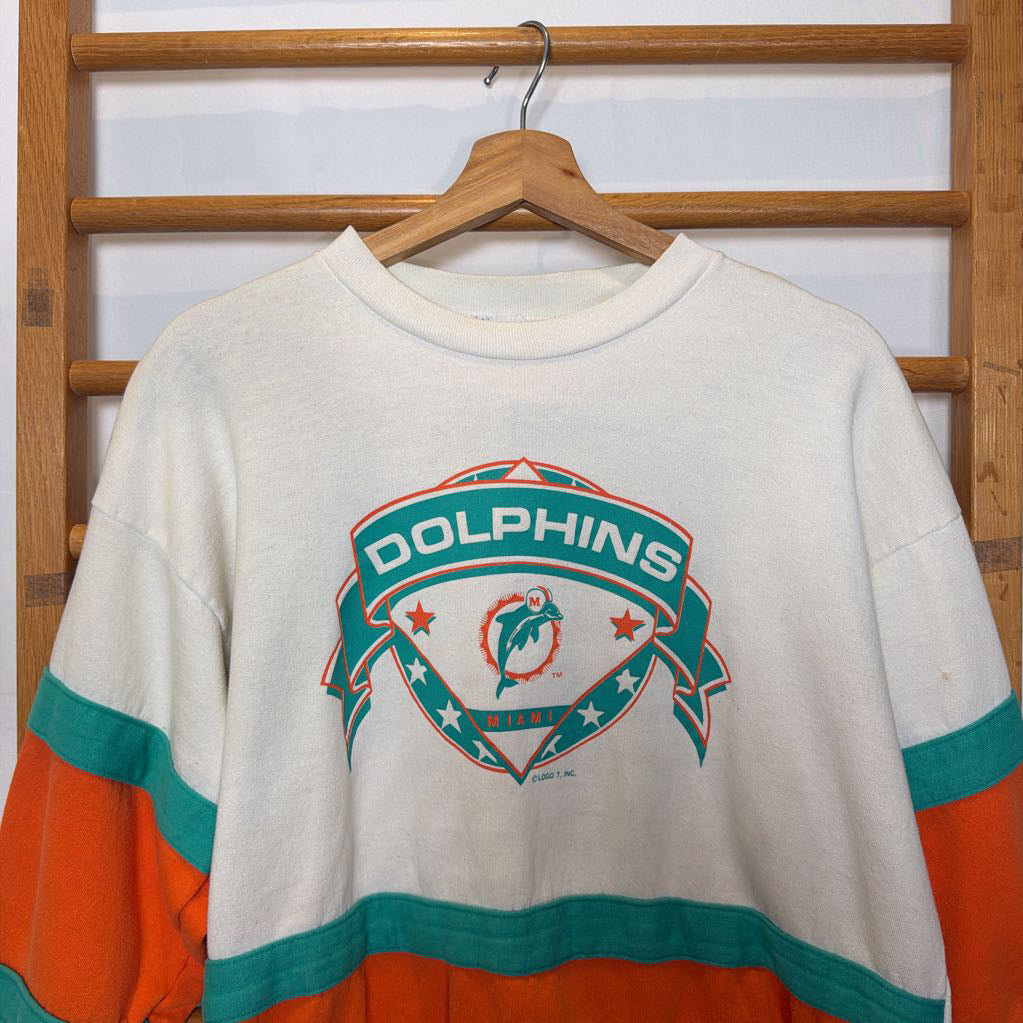 A white, orange, and turquoise Miami Dolphins branded sweatshirt on a wooden rack.  