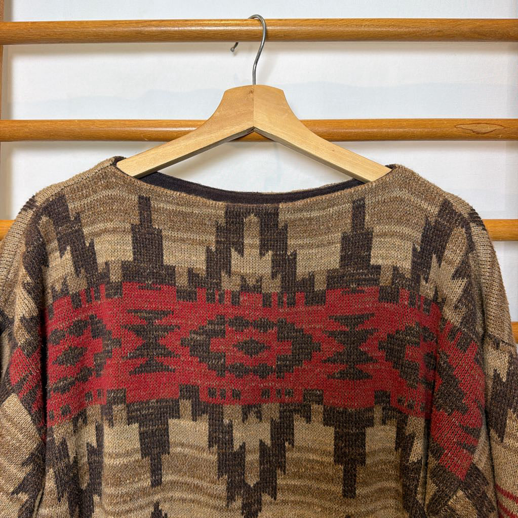 A short sleeve sweater with a tapestry design on a wooden rack. 