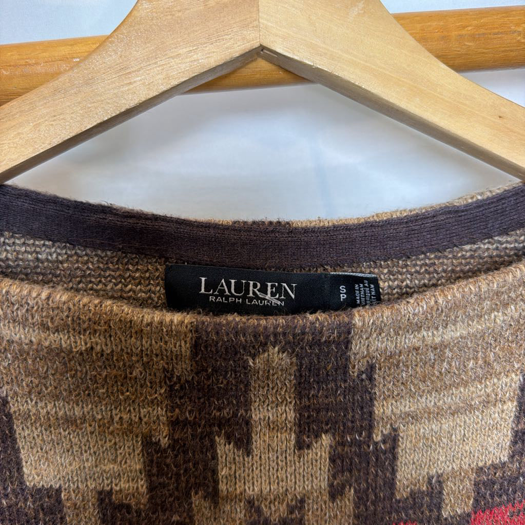 A short sleeve sweater with a tapestry design on a wooden rack. 
