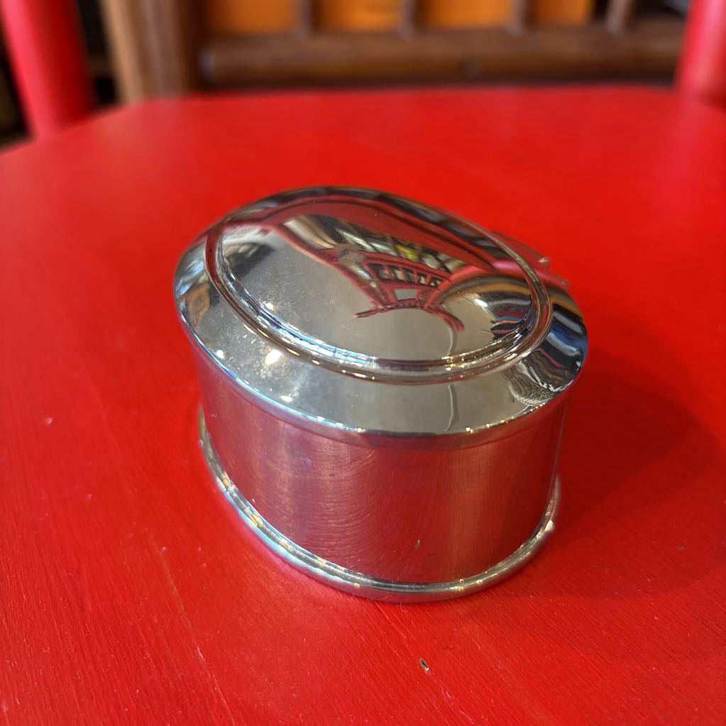 A silver jewelry box on a red surface.