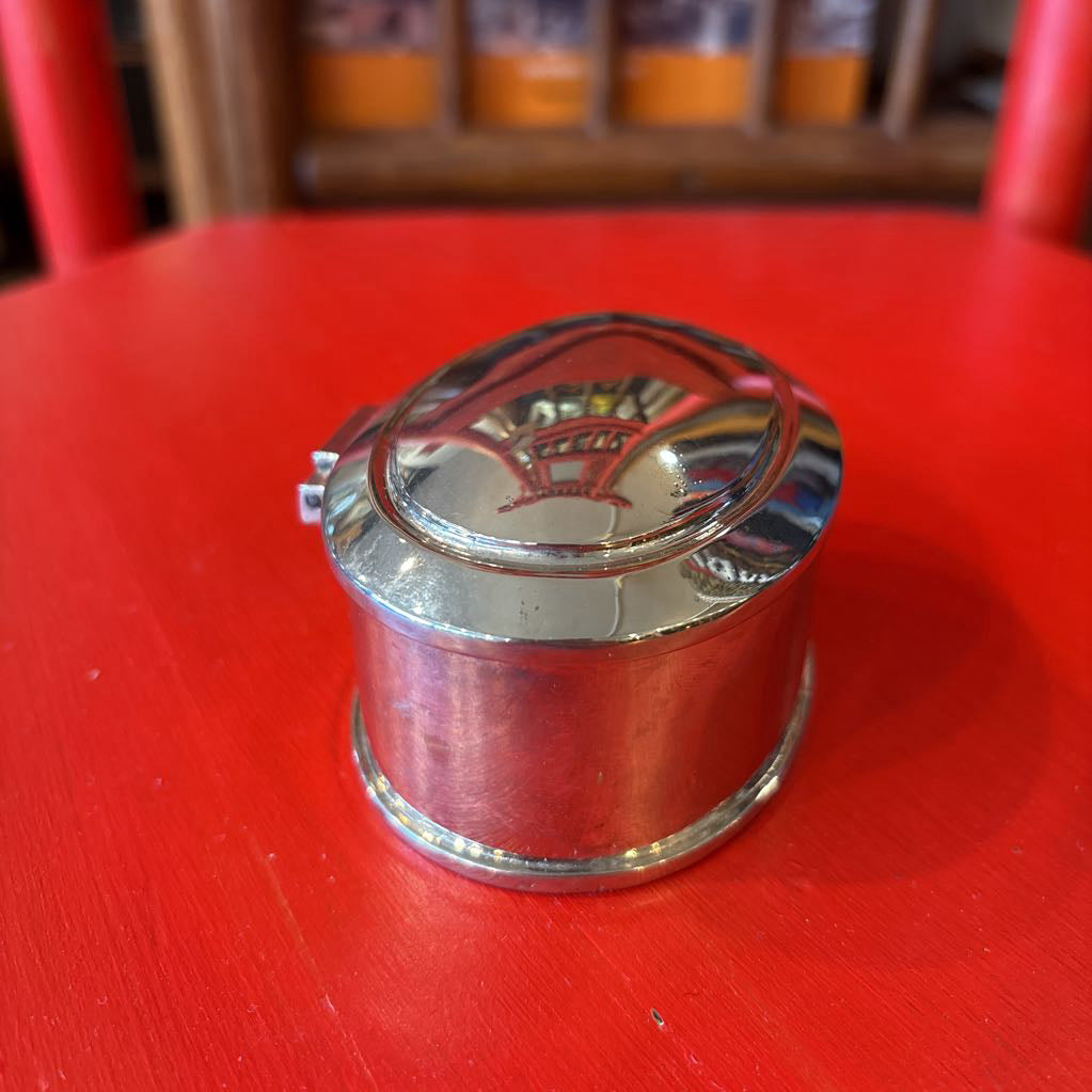 A silver jewelry box on a red surface. 