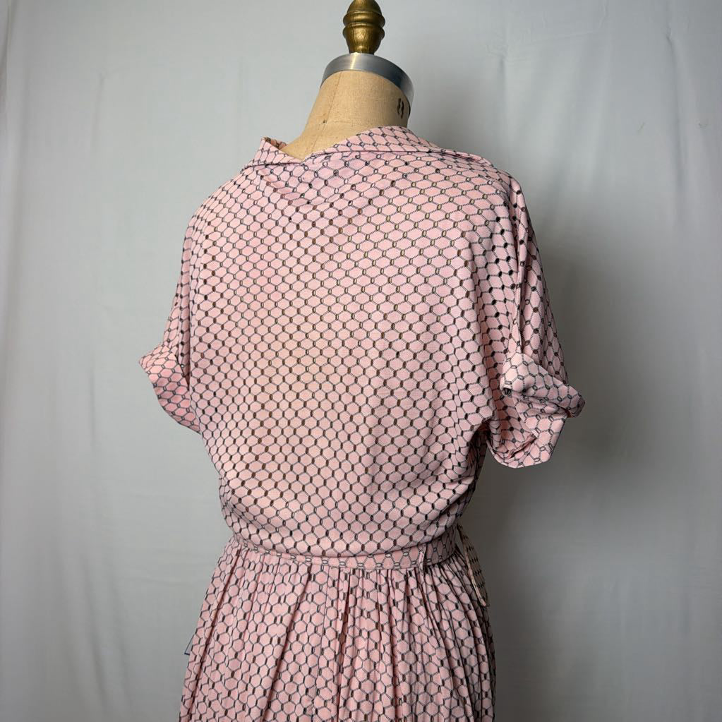 A light pink dress with cuffed sleeves and a belted waist on a mannequin in front of a white wall.