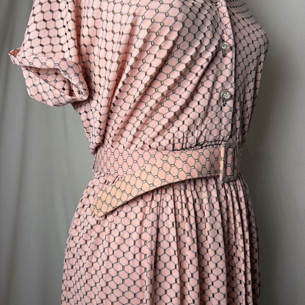 A light pink dress with cuffed sleeves and a belted waist on a mannequin in front of a white wall.