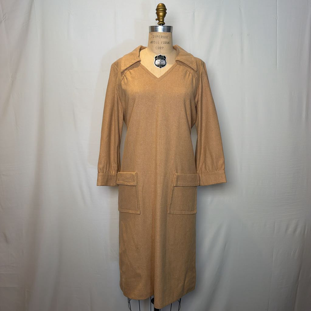 A long sleeve tan wool dress on a mannequin in front of a white wall. 