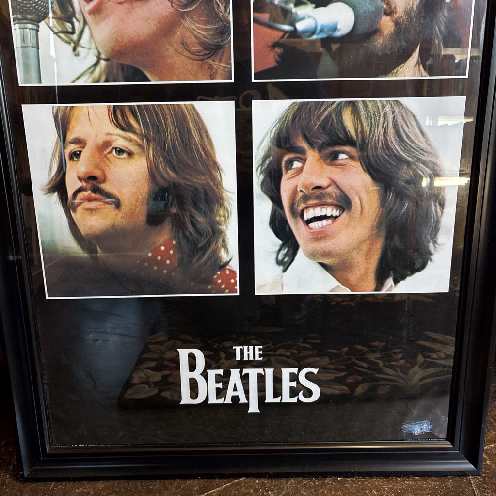 A black framed poster of the Beatles' album Let It Be leaning against a bookcase. 