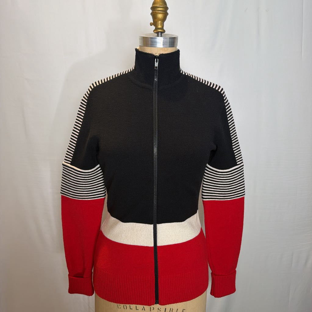 A black, red, and white color block zip-up jacket on a mannequin in front of a white wall.