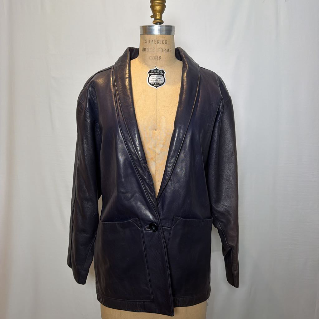 A navy leather trench jacket on a mannequin in front of a white wall. 
