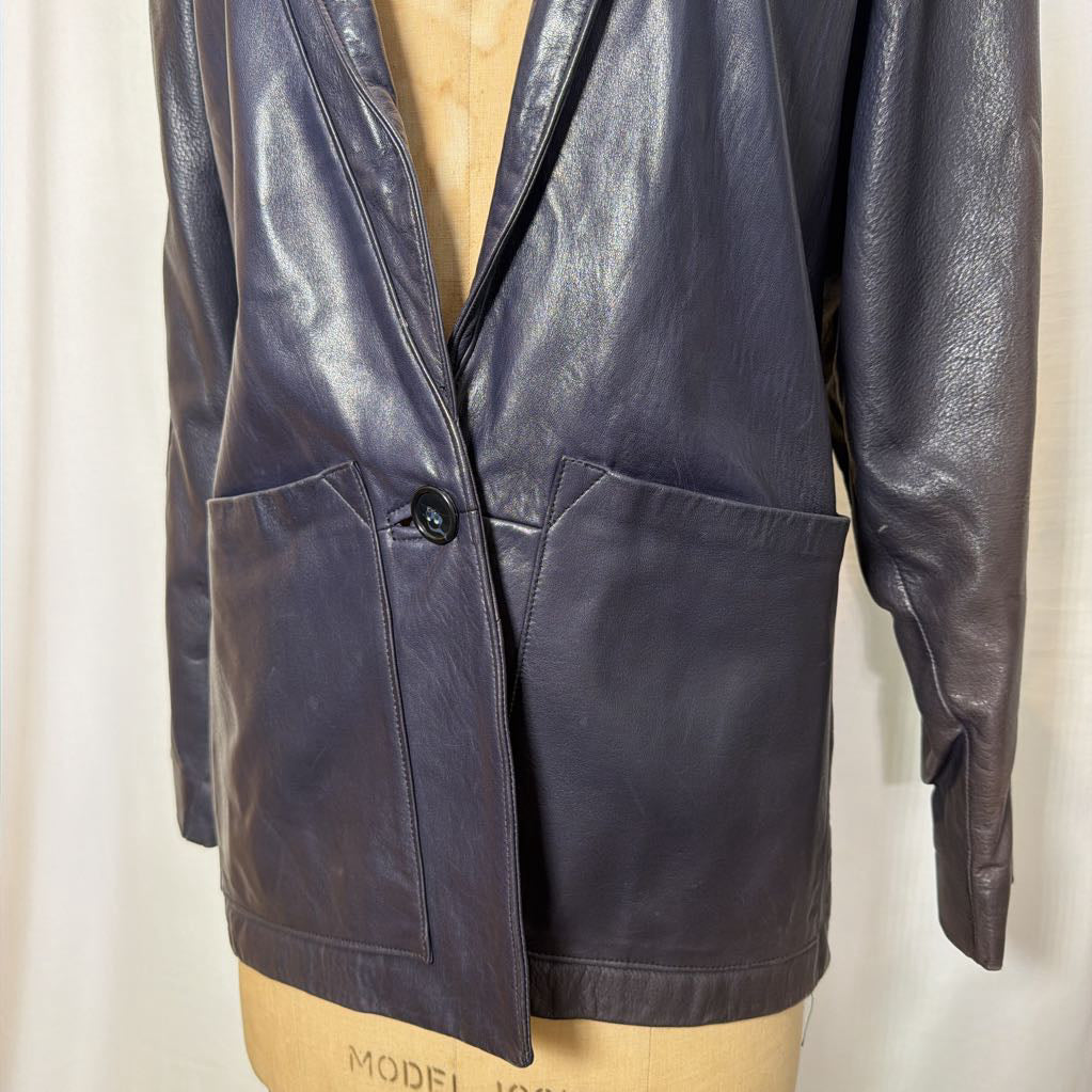 A navy leather trench jacket on a mannequin in front of a white wall. 