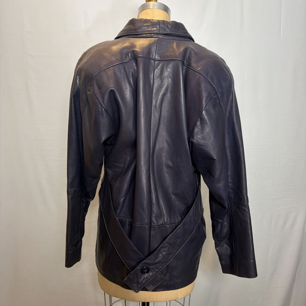A navy leather trench jacket on a mannequin in front of a white wall. 