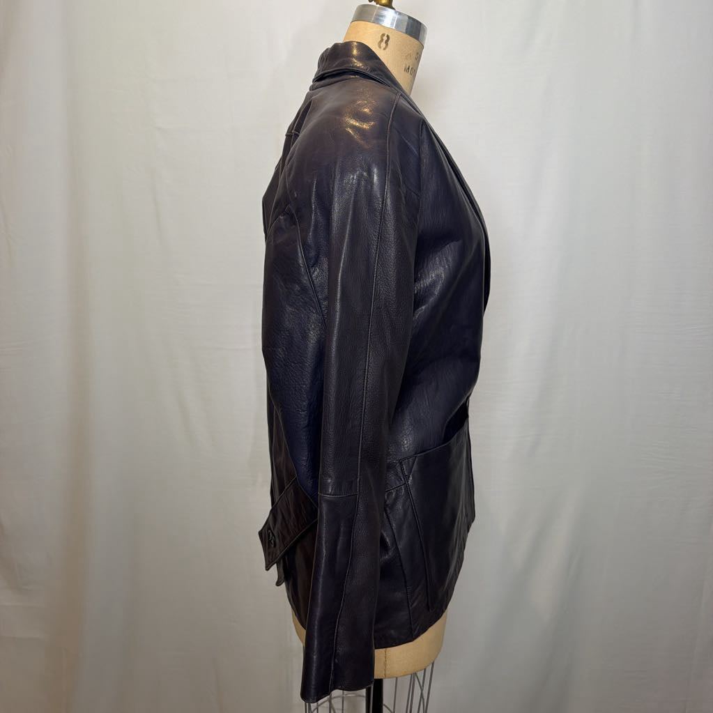 A navy leather trench jacket on a mannequin in front of a white wall. 