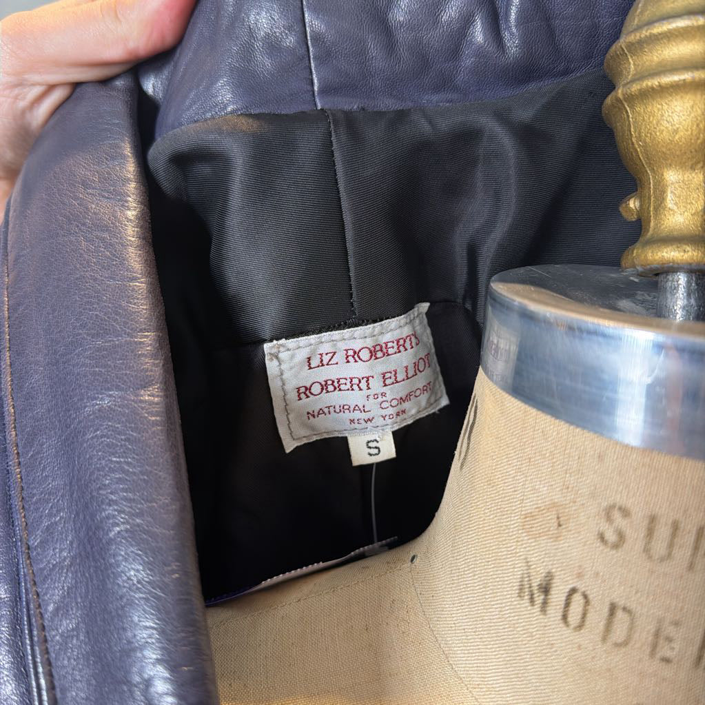A hand holding a brand tag in a leather jacket. 