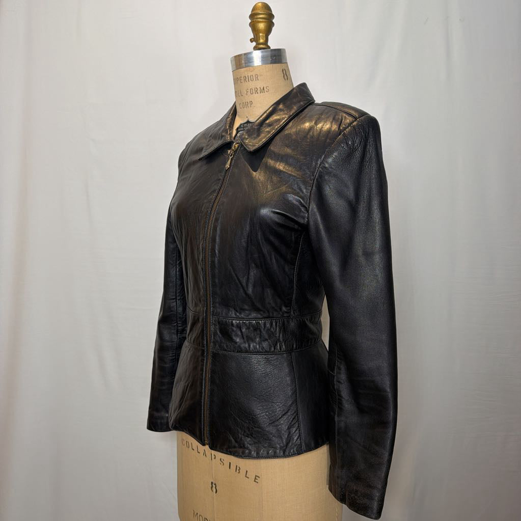A black zip-up leather jacket on a mannequin in front of a white wall.
