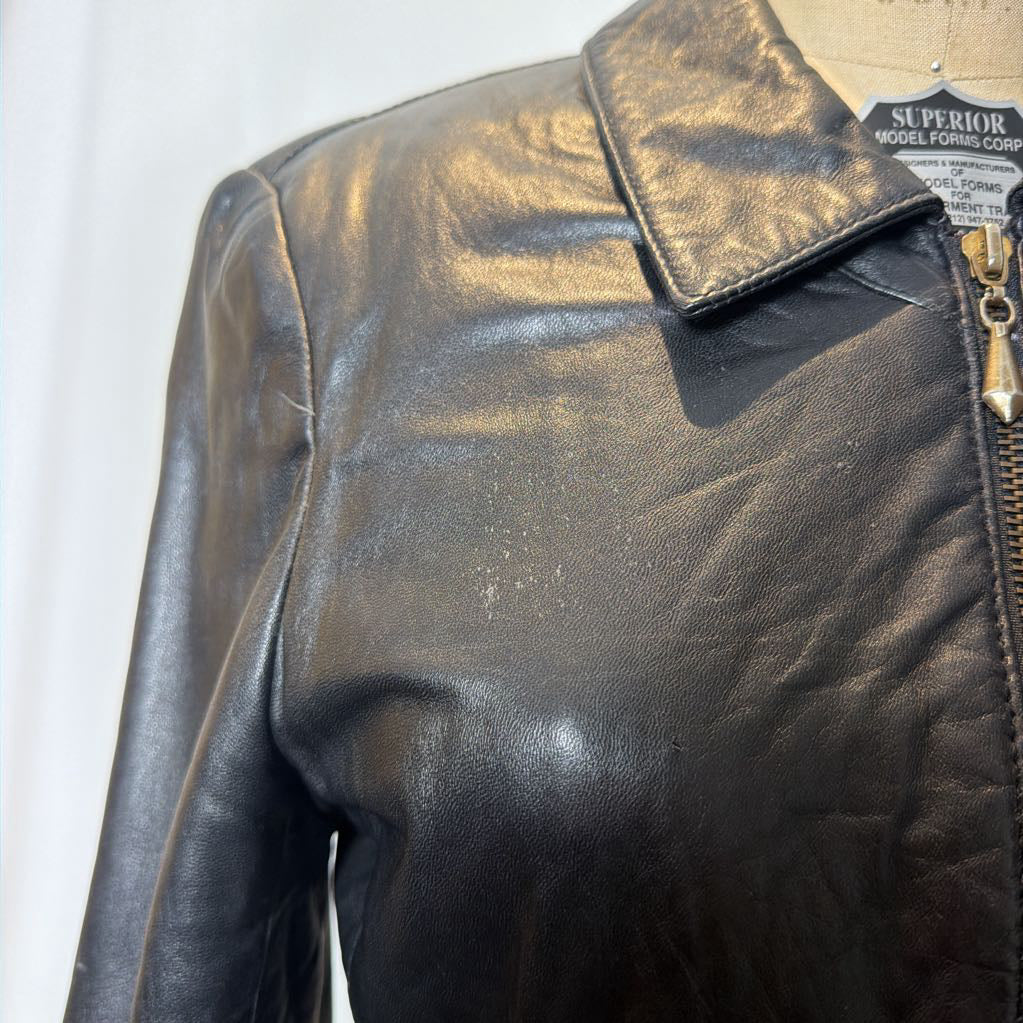A black zip-up leather jacket on a mannequin in front of a white wall.