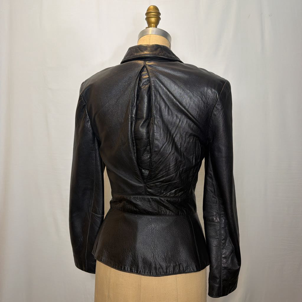 A black zip-up leather jacket on a mannequin in front of a white wall.