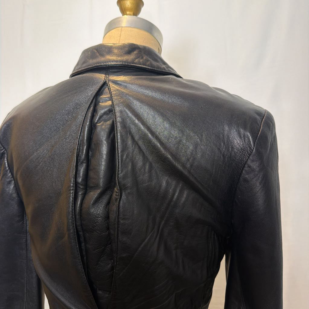 A black zip-up leather jacket on a mannequin in front of a white wall.