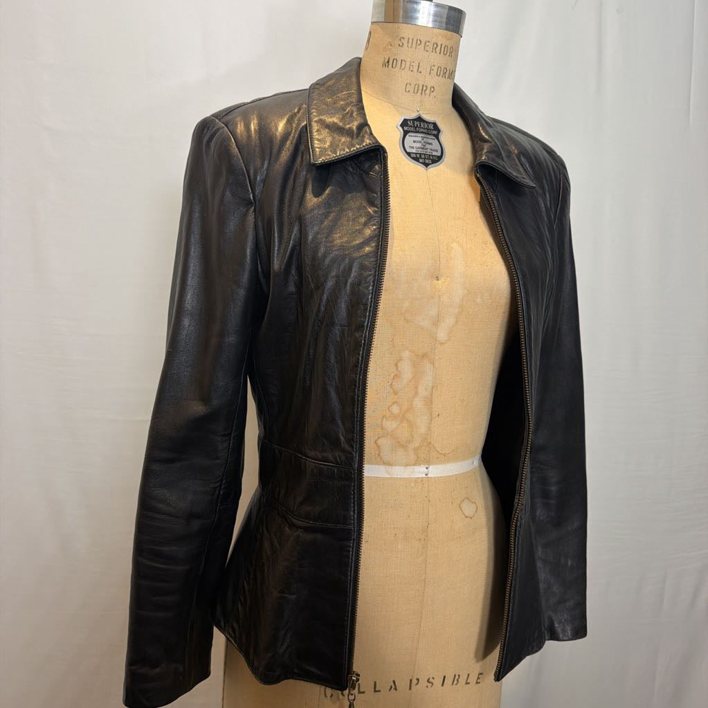 A black zip-up leather jacket on a mannequin in front of a white wall.