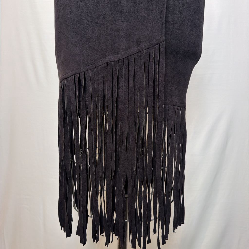 A black high-waisted skirt with a long asymmetrical fringe hem on a mannequin in front of a white wall. 