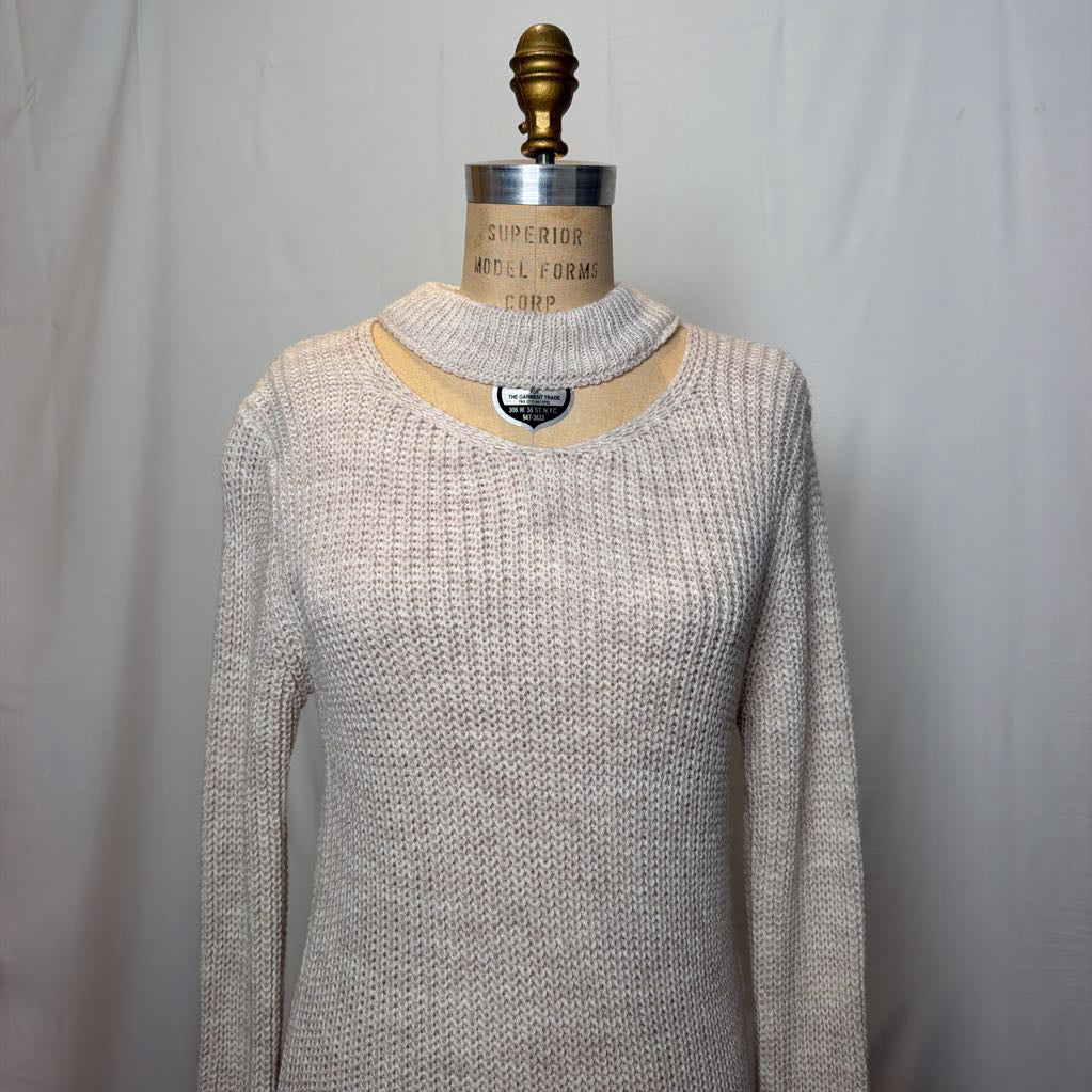 A white knit dress with an open neck and a slit on the bottom. It's on a mannequin in front of a white wall.