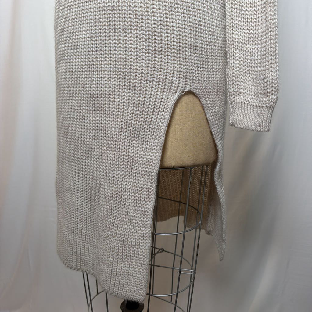 A white knit dress with an open neck and a slit on the bottom. It's on a mannequin in front of a white wall.