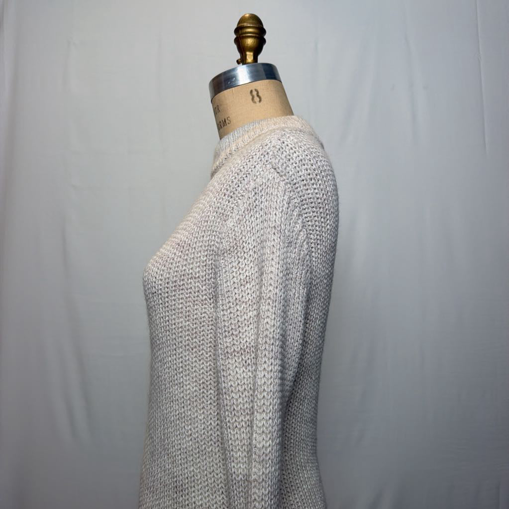 A white knit dress with an open neck and a slit on the bottom. It's on a mannequin in front of a white wall.