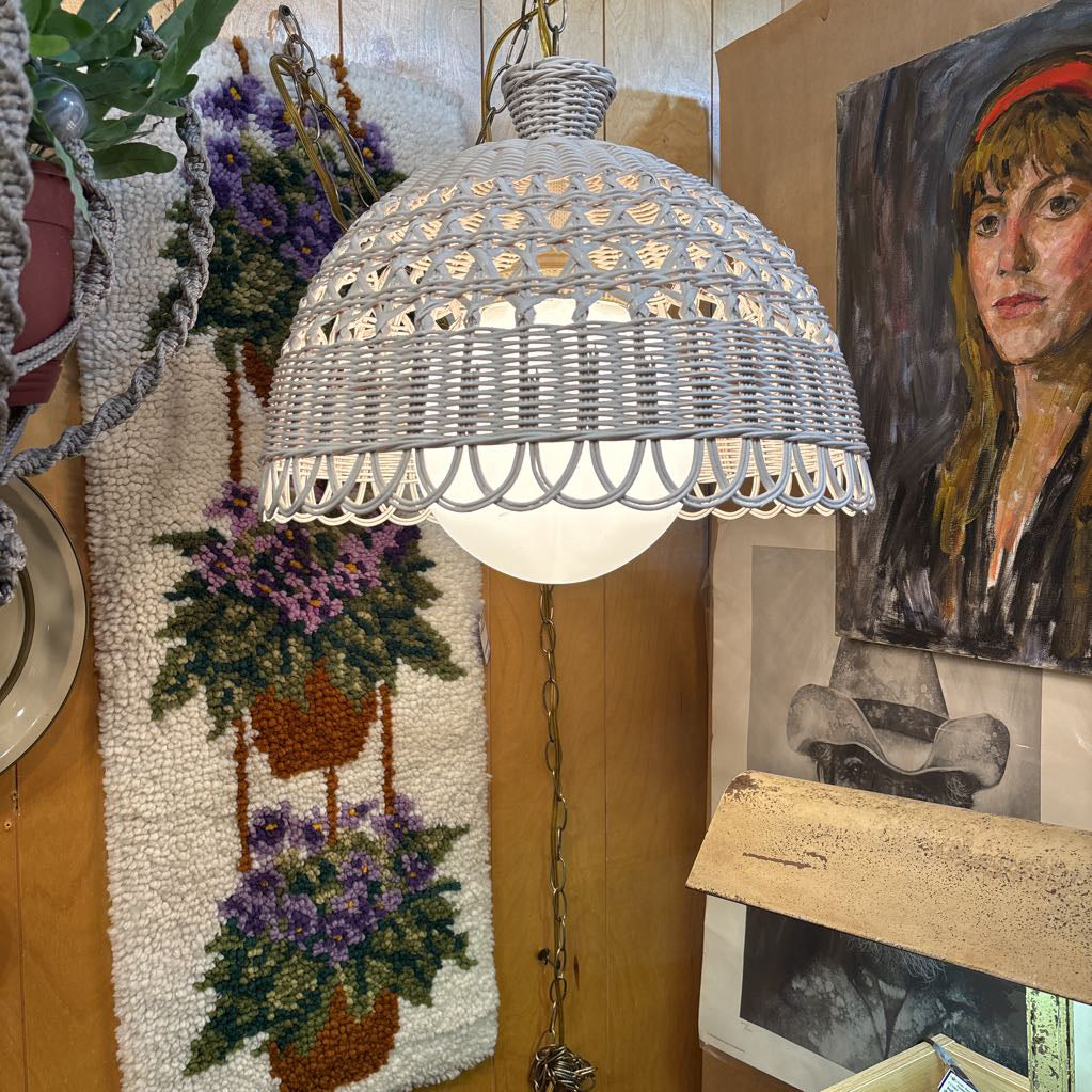 A white wicker shaded swag lamp hanging in a room setting.