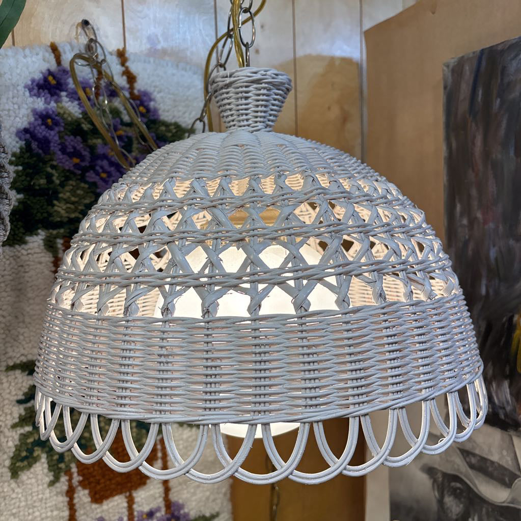 A white wicker shaded swag lamp hanging in a room setting.