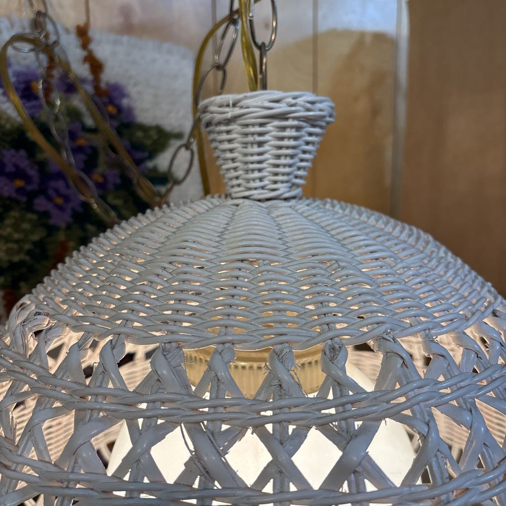 A white wicker shaded swag lamp hanging in a room setting.