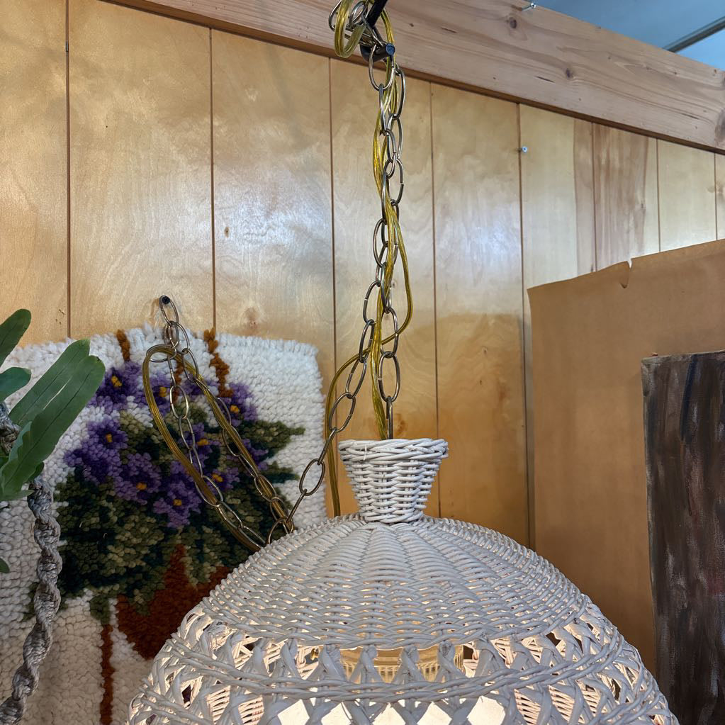 A white wicker shaded swag lamp hanging in a room setting.