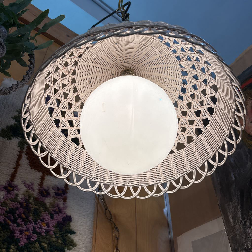 A white wicker shaded swag lamp hanging in a room setting.