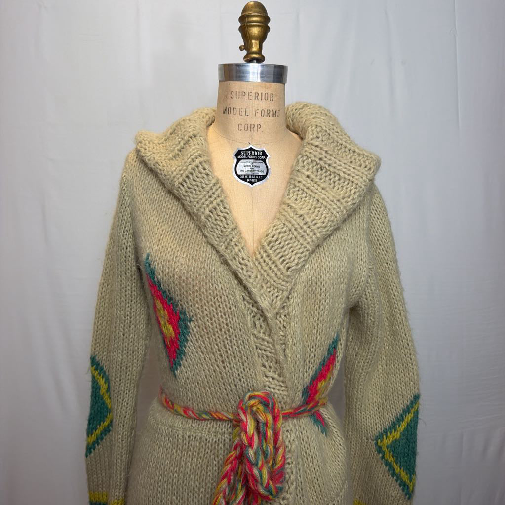 A tan belted knit sweater hoodie on a mannequin in front of a white wall.