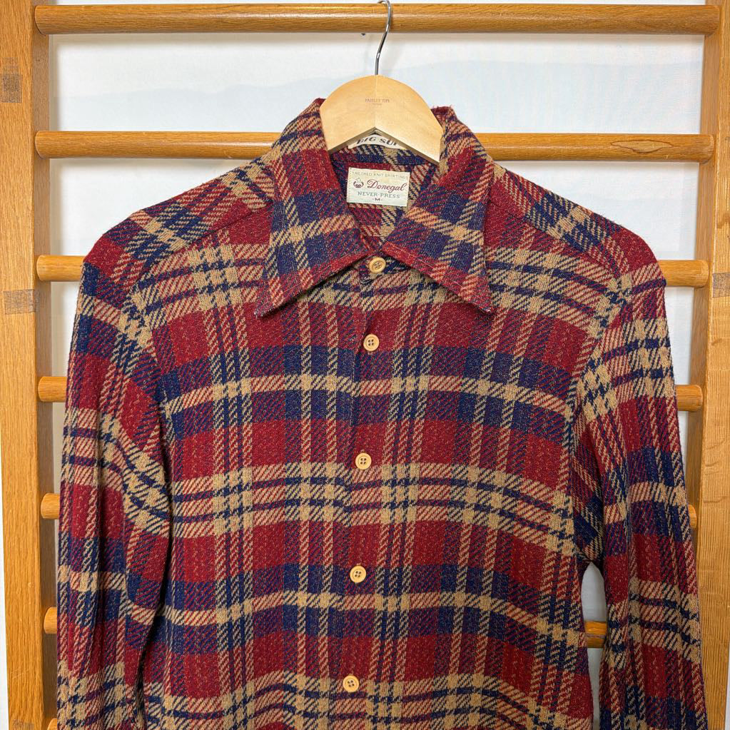 A button-up plaid shirt on a wooden rack. 