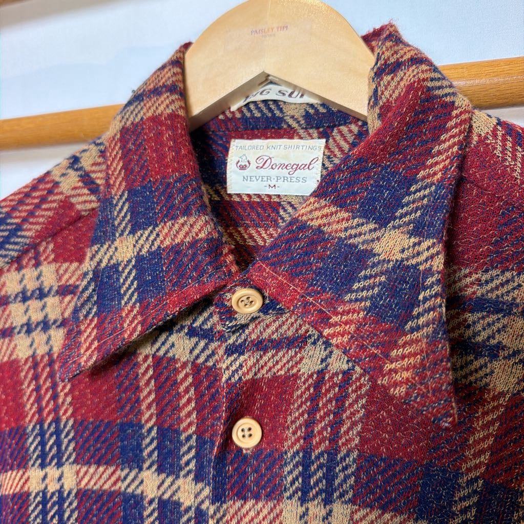 A button-up plaid shirt on a wooden rack. 