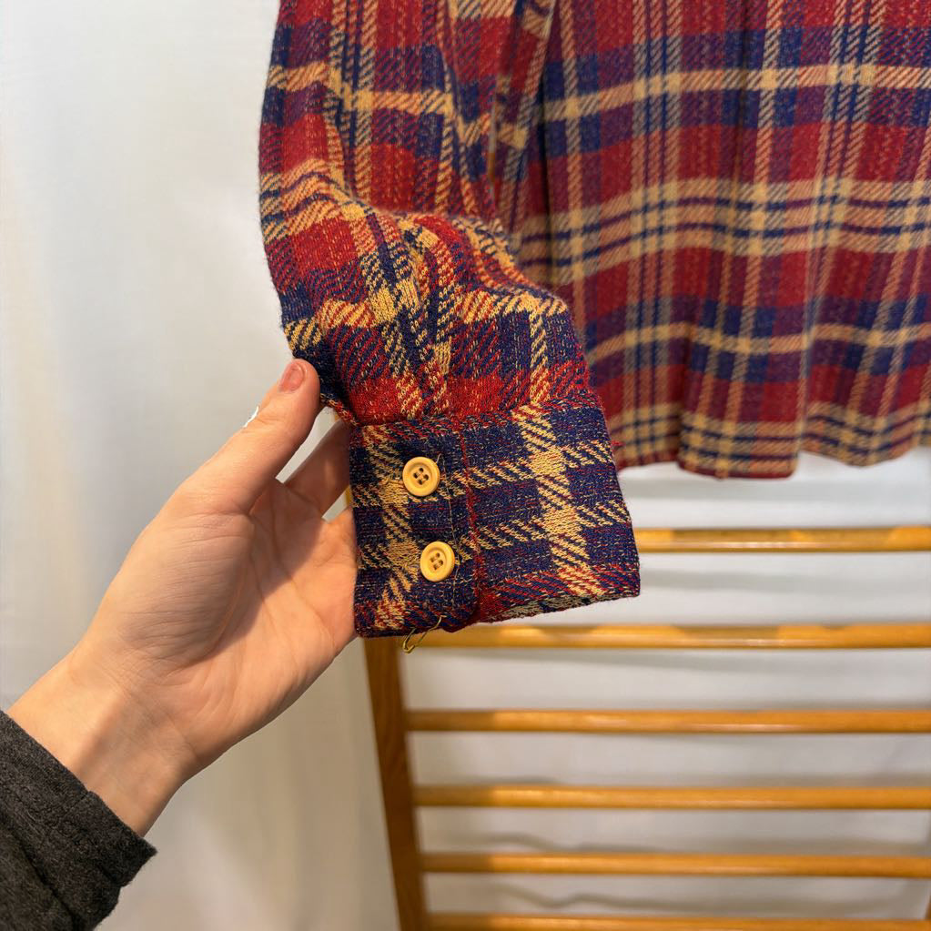 A button-up plaid shirt on a wooden rack. 