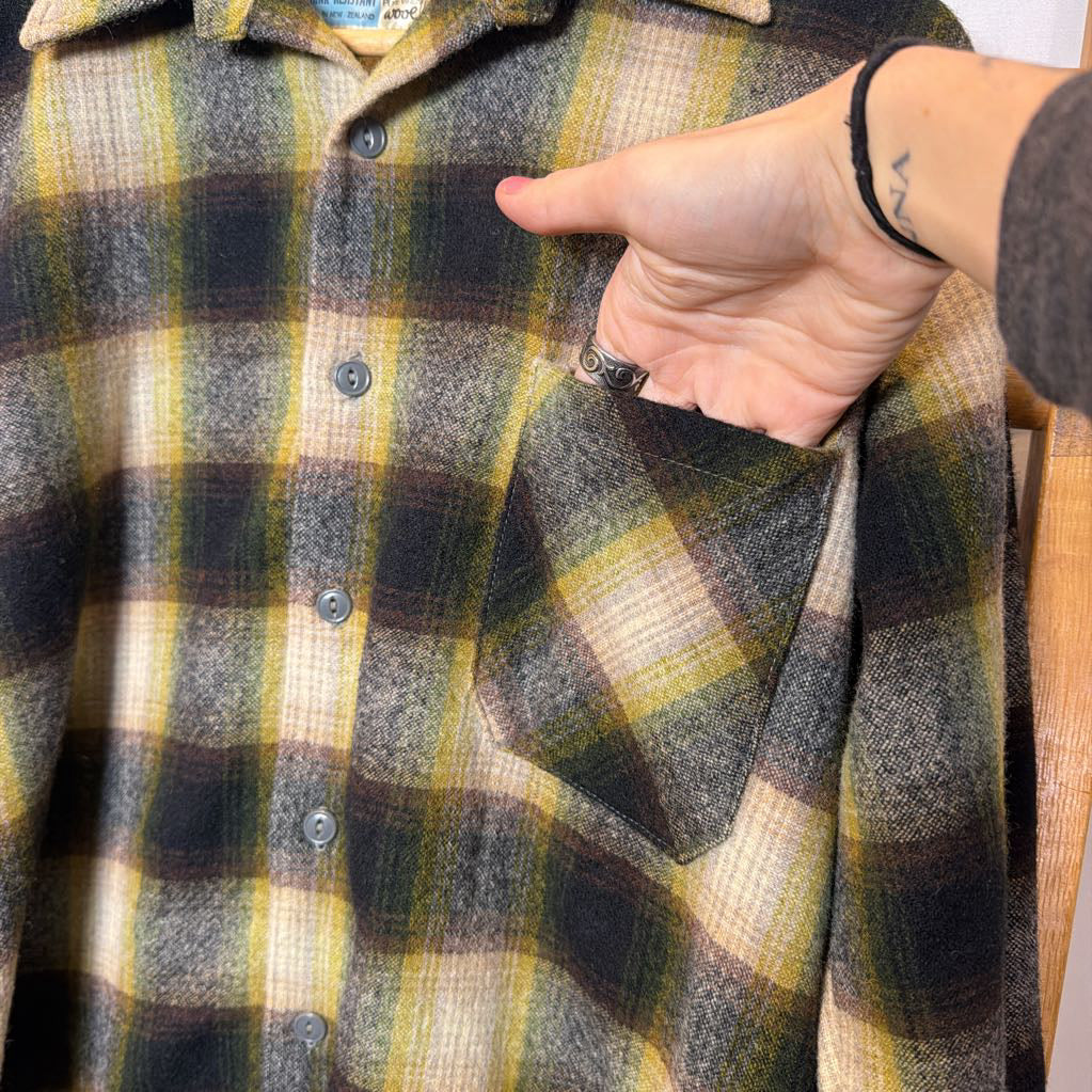 A green ombre plaid button-up shirt on a wooden rack. 