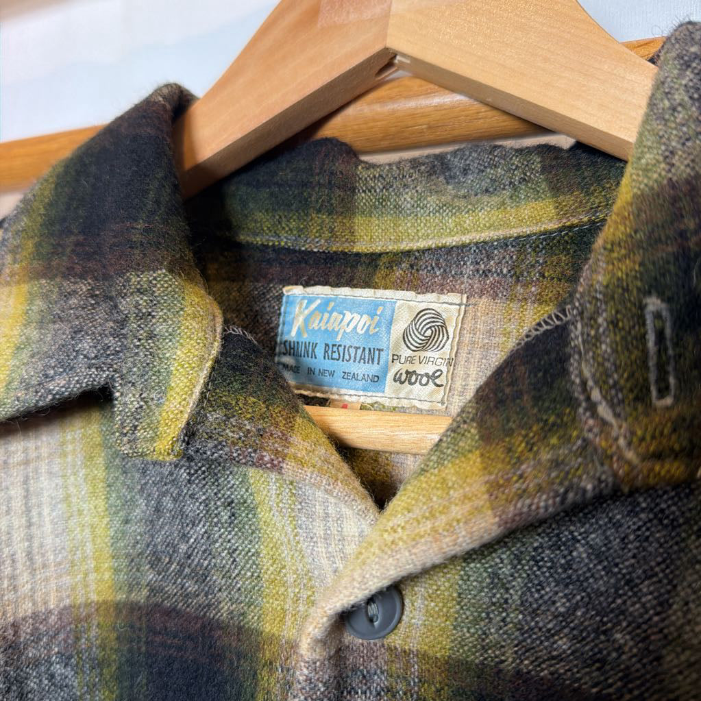 A green ombre plaid button-up shirt on a wooden rack. 