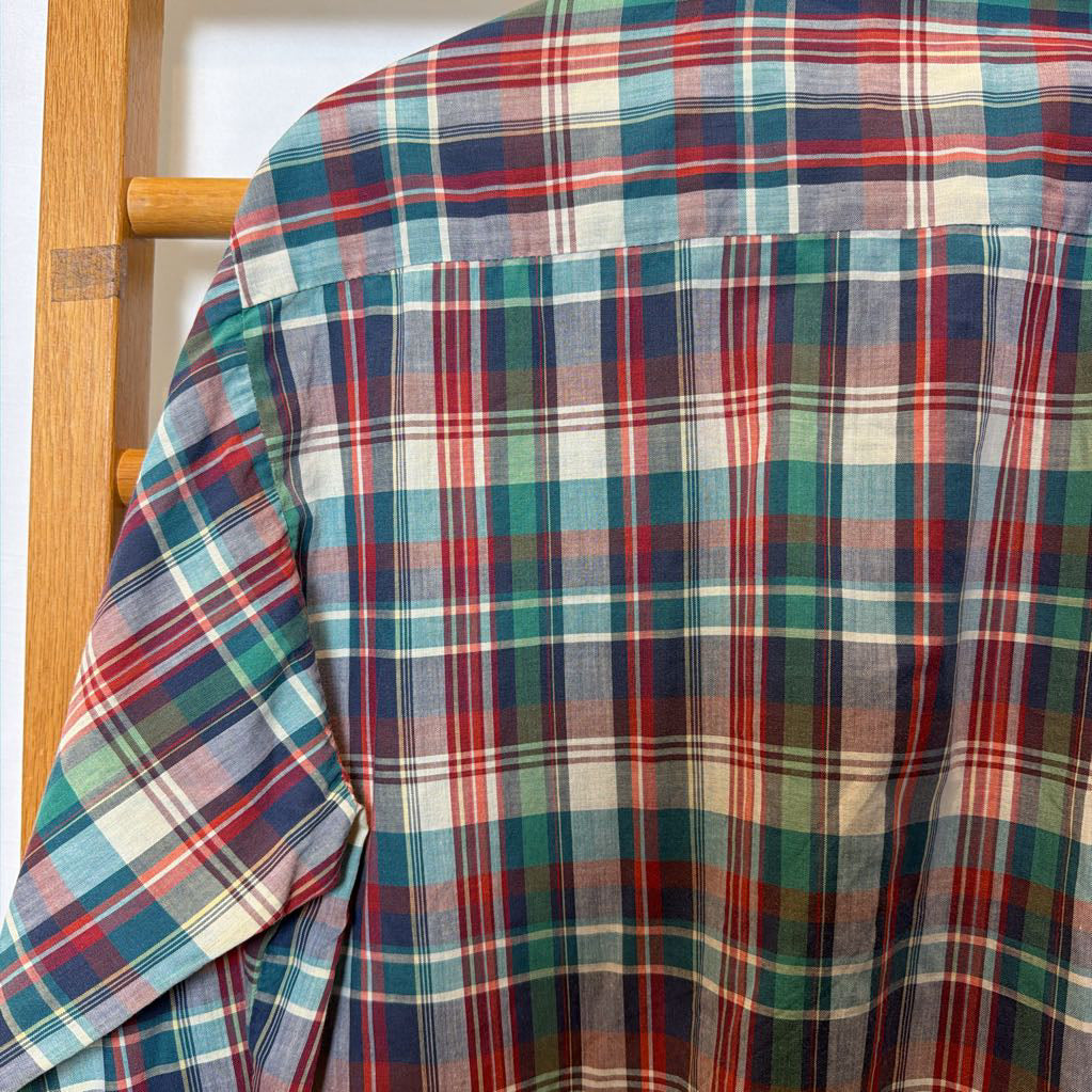 A plaid button-up shirt on a wooden rack.