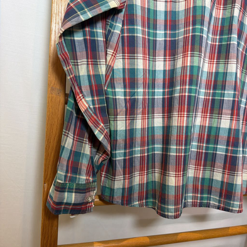A plaid button-up shirt on a wooden rack.