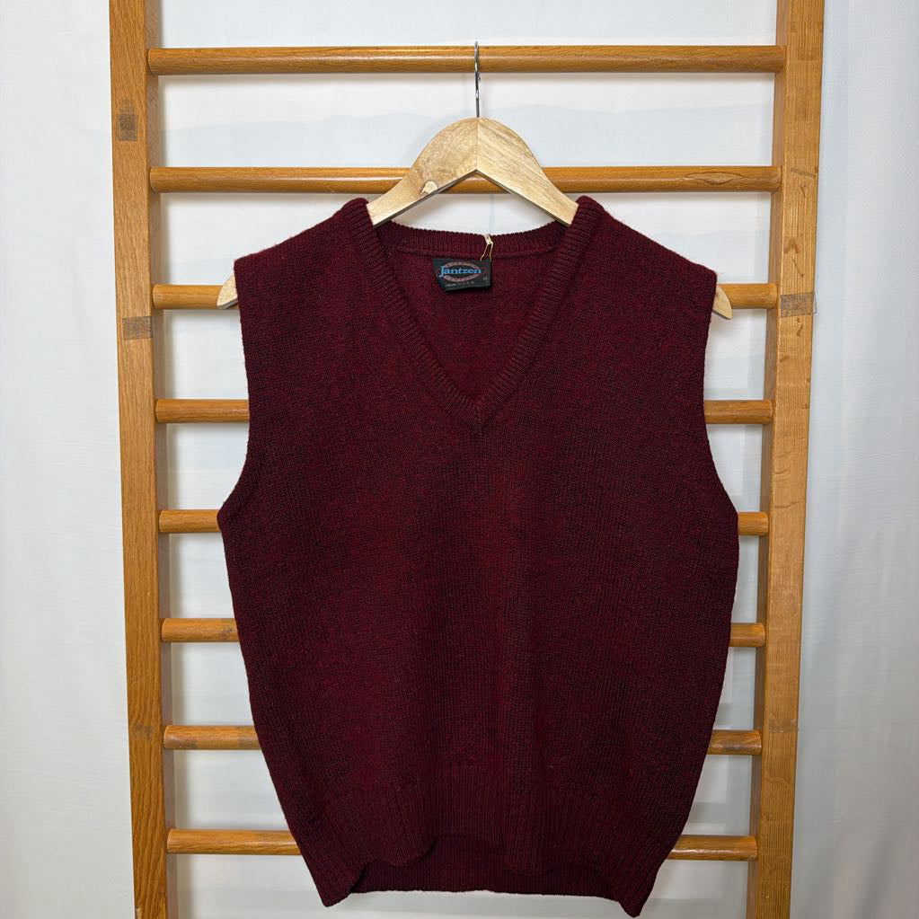 A maroon sweater vest on a wooden rack.