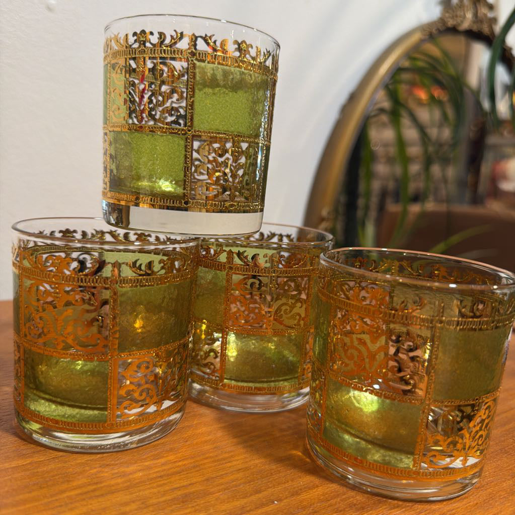 Four culver prado green glassware featuring a pale green tine and ornate 22k gold filigree checkerboard panels sitting on wood. 
