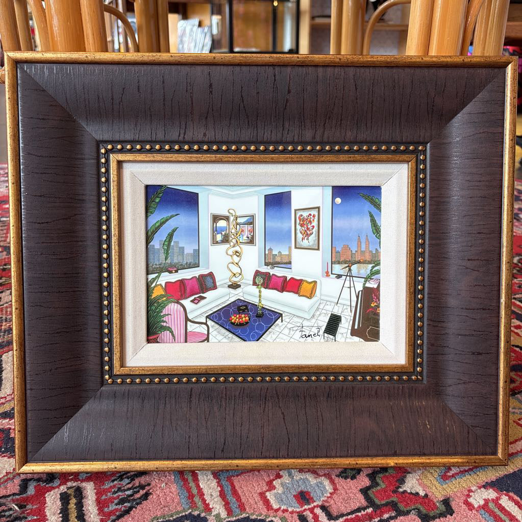 A framed artwork of a room and a nigh time cityscape outside of the windows. 